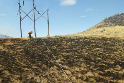 Firefighters working at the edge of a forest wildfire amid smoke